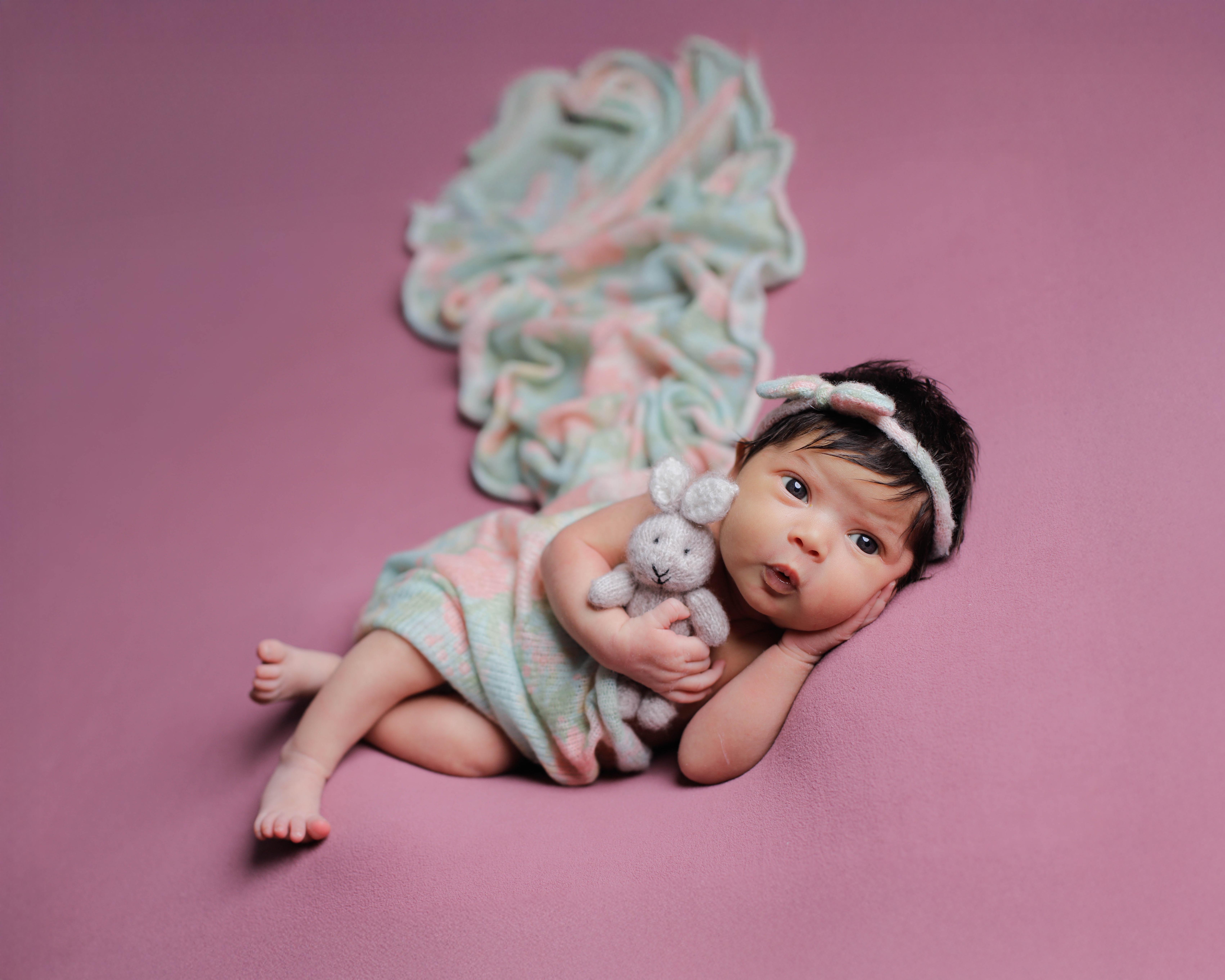 A newborn wrapped against a warm grey studio backdrop.
